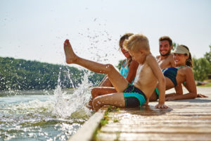 Familie am See badet glücklich mit Füßen im Wasser im Sommer